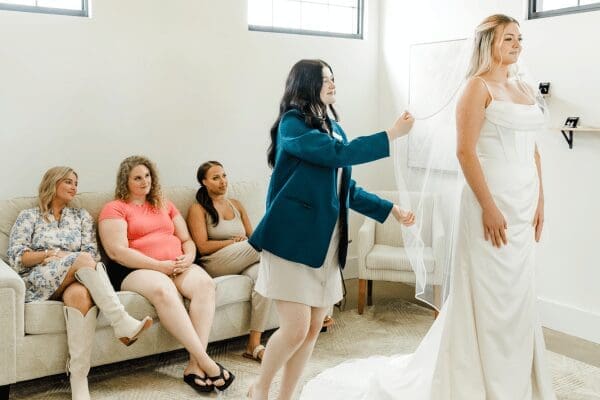 The bride trying on her wedding dress while her bridal party notices how beautiful she is