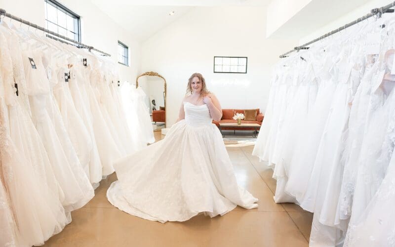 Bride trying on a wedding dress in a bridal boutique surrounded by gowns