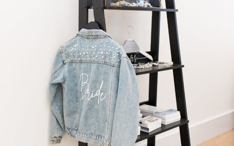 Bride denim jacket with pearl details displayed alongside bridal accessories
