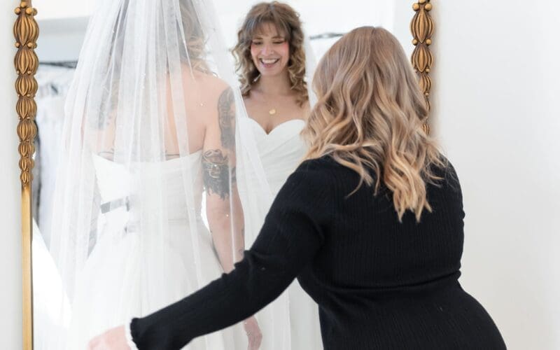 Bride trying on a wedding dress with a stylist during a bridal fitting appointment