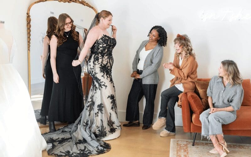 Bride trying on a wedding gown with friends during wedding dress shopping