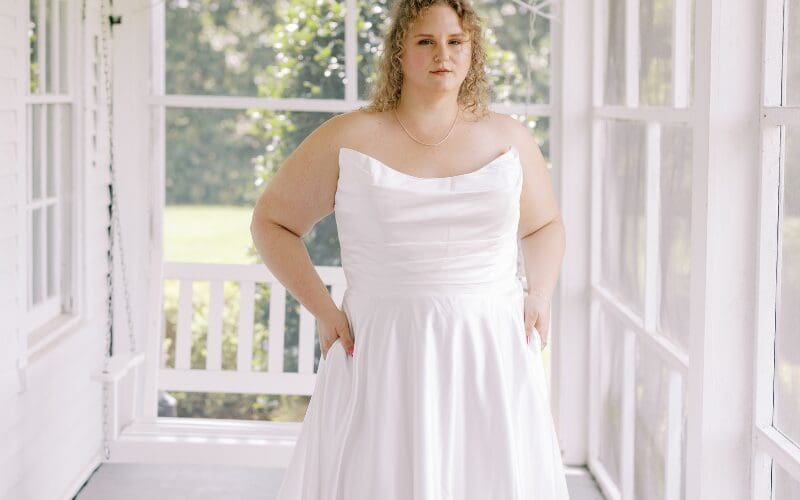 Curvy bride wearing a satin wedding dress with a draped neckline