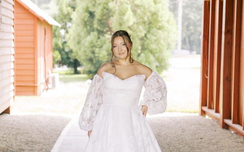 Bride posing in a lace wedding dress with an off-the-shoulder neckline