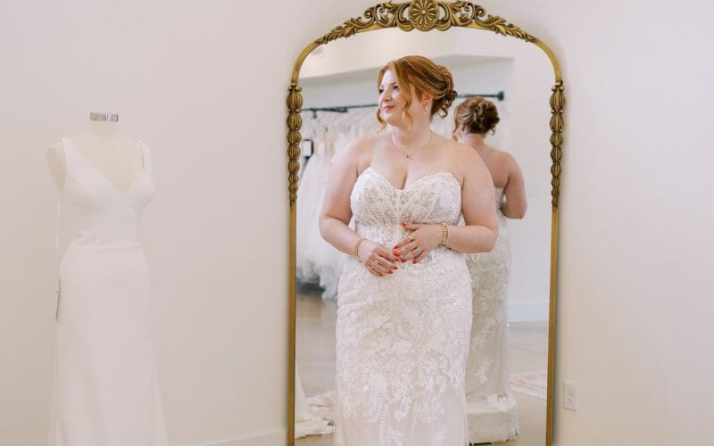 Bride looking at herself in the mirror while wearing a lace wedding gown
