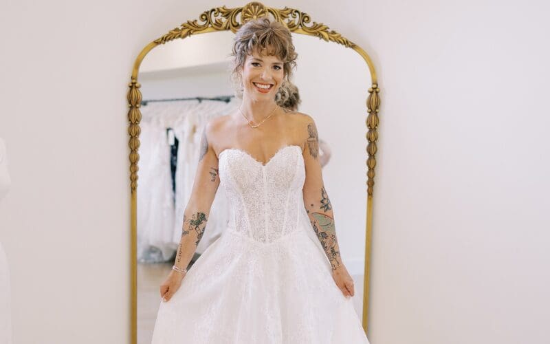 Bride smiling in a strapless lace wedding dress during her bridal appointment