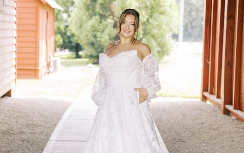Bride wearing a white off-the-shoulder wedding dress with long sleeves